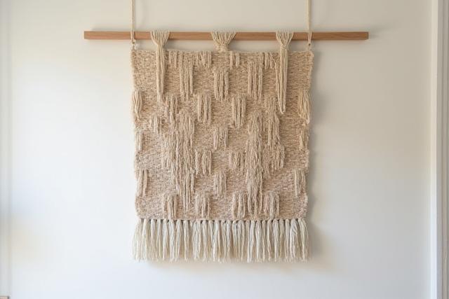 Pièce d'art textile contemporain avec des textures variées sur un mur clair